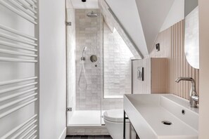 Une salle de bain moderne avec une douche à parois de verre, un lavabo blanc et un miroir.