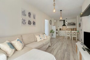 A modern living room with a sofa, a dining area, and a kitchen.