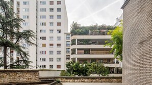 Un edifici residencial de diversos pisos amb balcons, un mur de pedra de contenció i una escala de fusta.