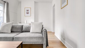 A modern living room with a grey sofa, a wooden coffee table, and a hanging light fixture. - Blueground | Ecole Militaire, furnished, balcony (Paris)