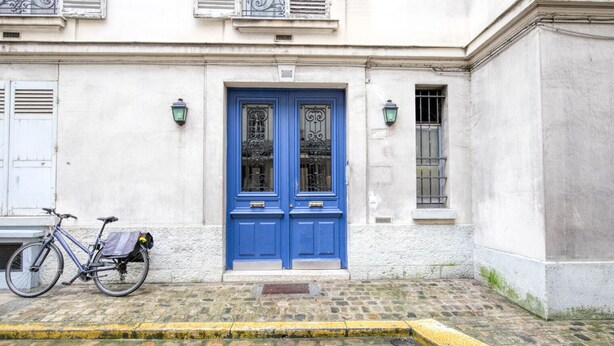 A building with a blue door and a bicycle parked in front. - Blueground | Ecole Militaire, furnished, balcony (Paris)