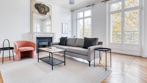 Una sala de estar con chimenea, un sofá, una mesa de centro y dos mesitas auxiliares.