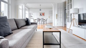 Una sala de estar moderna con un sofá gris, una mesa de centro y un televisor sobre un soporte de madera.