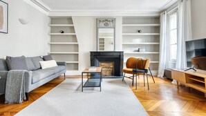 Uma sala de estar moderna com sofá, mesa de centro, lareira e rack para TV.