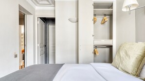 Quarto de hotel com uma cama, um guarda-roupa e um cabideiro.