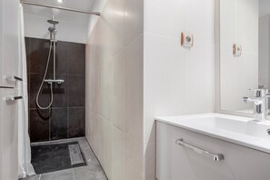 Une salle de bain moderne équipée d’une douche, d’un lavabo et d’un miroir.