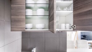 A modern kitchen with grey tiles, a white sink, and wooden cabinets. - Blueground | Palais Royal, balcony, nr Louvre (Paris)
