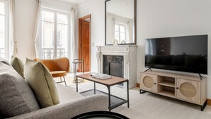 Un salon comprenant un canapé, un téléviseur, une cheminée et un grand miroir.