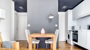 Eine moderne Küche mit integriertem Waschtrockner, einer Essecke mit Holztisch und grauen Stühlen sowie einer Wand in Grau als Akzent.