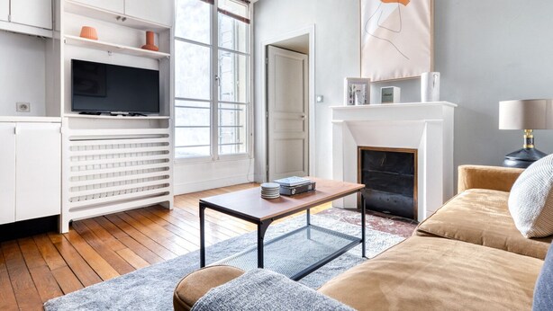 Ein modernes Wohnzimmer mit Kamin, Fernseher und Sofa.