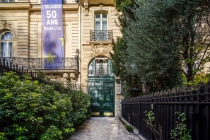 A historic building with a green double door, ornate iron railings, and a banner celebrating 50 years. - Blueground | Arc de Triomphe, nr Champs Elysées (Paris)