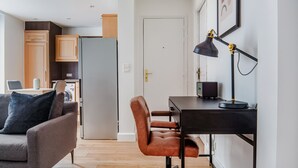 A modern living room with a sofa, a desk with a chair, a lamp, and a television. - Blueground | Arc de Triomphe, nr Champs Elysées (Paris)