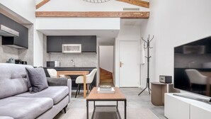 A modern living room with a grey sofa, a coffee table, and a TV. - Blueground | Monceau, a/c, nr Parc Monceau (Paris)