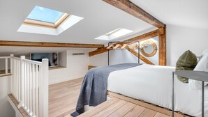 A bedroom with skylights, a bed, a TV, and a wooden ceiling. - Blueground | Monceau, a/c, nr Parc Monceau (Paris)
