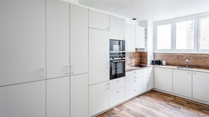 A modern kitchen with white cabinetry, a built-in oven, and a wooden backsplash. - Blueground | Miromesnil, furnished, elevator (Paris)