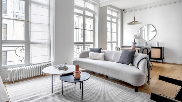 A modern living room with a sofa, a coffee table, and a dining area.