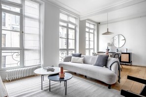 A modern living room with a sofa, a coffee table, and a dining area. - Blueground | Sentier Montorgueil, furnished (Paris)