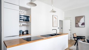 A modern kitchen with a wooden countertop, built-in appliances, and pendant lighting.