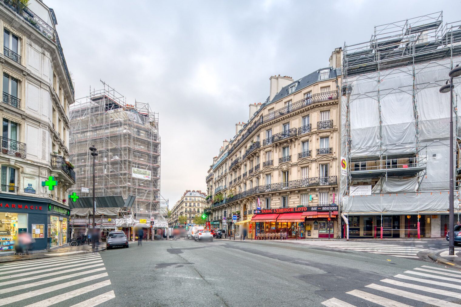A street view with buildings, including a pharmacy and a bar on the right.