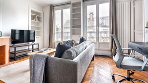 Ein modernes Wohnzimmer mit einer Couch, einem Fernseher und einem Schreibtisch.