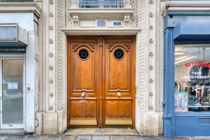 A double wooden door with a sign above it. - Blueground | Le Marais, elev, nr Rambuteau St (Paris)