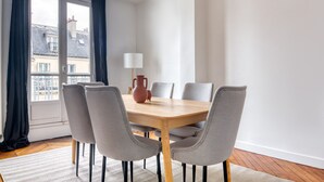 Ein Essbereich mit einem Holztisch, sechs grauen Stühlen, einer Vase und einer Lampe.