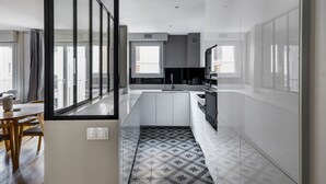 A modern kitchen with white cabinetry, a central island, and a patterned backsplash. - Blueground | Porte de Champerret, elevator (Paris)