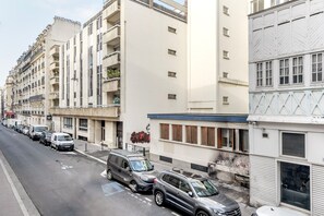 Eine Reihe geparkter Autos säumt eine Straße mit mehrstöckigen Gebäuden, die Balkone und verschiedene Architekturstile aufweisen.