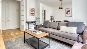 A modern living room with a grey sofa, a wooden coffee table, and a desk with a chair. - Blueground | Rochechouart, nr Rue de Martyrs (Paris)