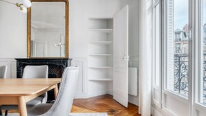 Et spiseområde med et træbord og stole, en sort pejs, en hvid dør ind til et skab og udsigt over byen gennem store vinduer.