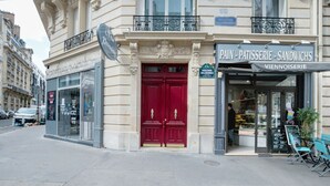 En butik med rødt dør og et skilt for et bageri ved navn "Pain - Pâtisserie - Sandwichs".