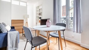 Un salon moderne avec une table de salle à manger ronde, deux chaises, un canapé, une lampe et une bibliothèque.