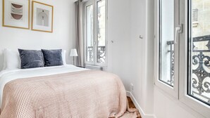 Une chambre à coucher avec un lit, deux oreillers, une lampe de chevet et deux œuvres d’art encadrées accrochées au mur.