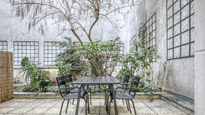 A courtyard with a table and chairs, surrounded by plants and a tree. - Blueground | Saint Georges, terrace, nr Montmartre (Paris)