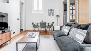 Una sala de estar moderna con un sofá gris, una mesa de centro de madera y un comedor con una mesa y sillas.
