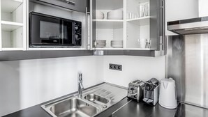 Una cocina moderna con microondas integrado, electrodomésticos de acero inoxidable y un lavamanos.