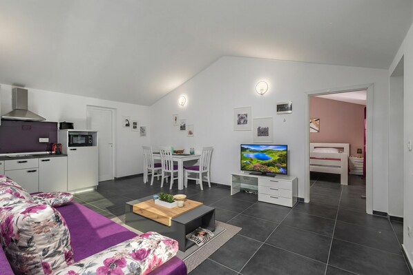 A modern apartment with a kitchen, dining area, living room, and a bedroom.