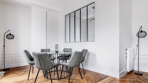 Un comedor moderno con una mesa redonda, sillas tapizadas en gris y un espejo grande en la pared.