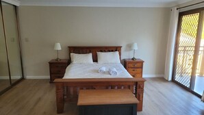 A bedroom with a wooden bed, two bedside tables, and a bench.