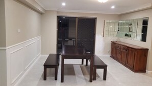 A dining area with a dark wooden table and benches, a cabinet, and a sliding glass door leading to another room.