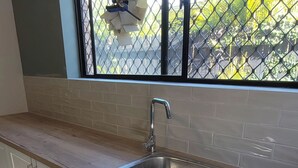 A kitchen with a stainless steel sink, white cabinets, and a wooden countertop.