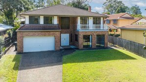 A two-story house with a garage, a balcony, and a well-maintained lawn.