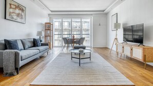 A modern living room with a grey sofa, a coffee table, and a TV on a wooden cabinet.