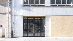 A modern building entrance with a glass door and a wooden panel on the right.
