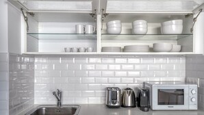Eine moderne Küche mit Spüle aus Edelstahl, Toaster, Wasserkocher, Kaffeemaschine und Mikrowelle.