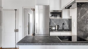 A modern kitchen with a stainless steel refrigerator, a microwave, and a built-in oven. - Blueground | Sèvres, near shopping (Paris)