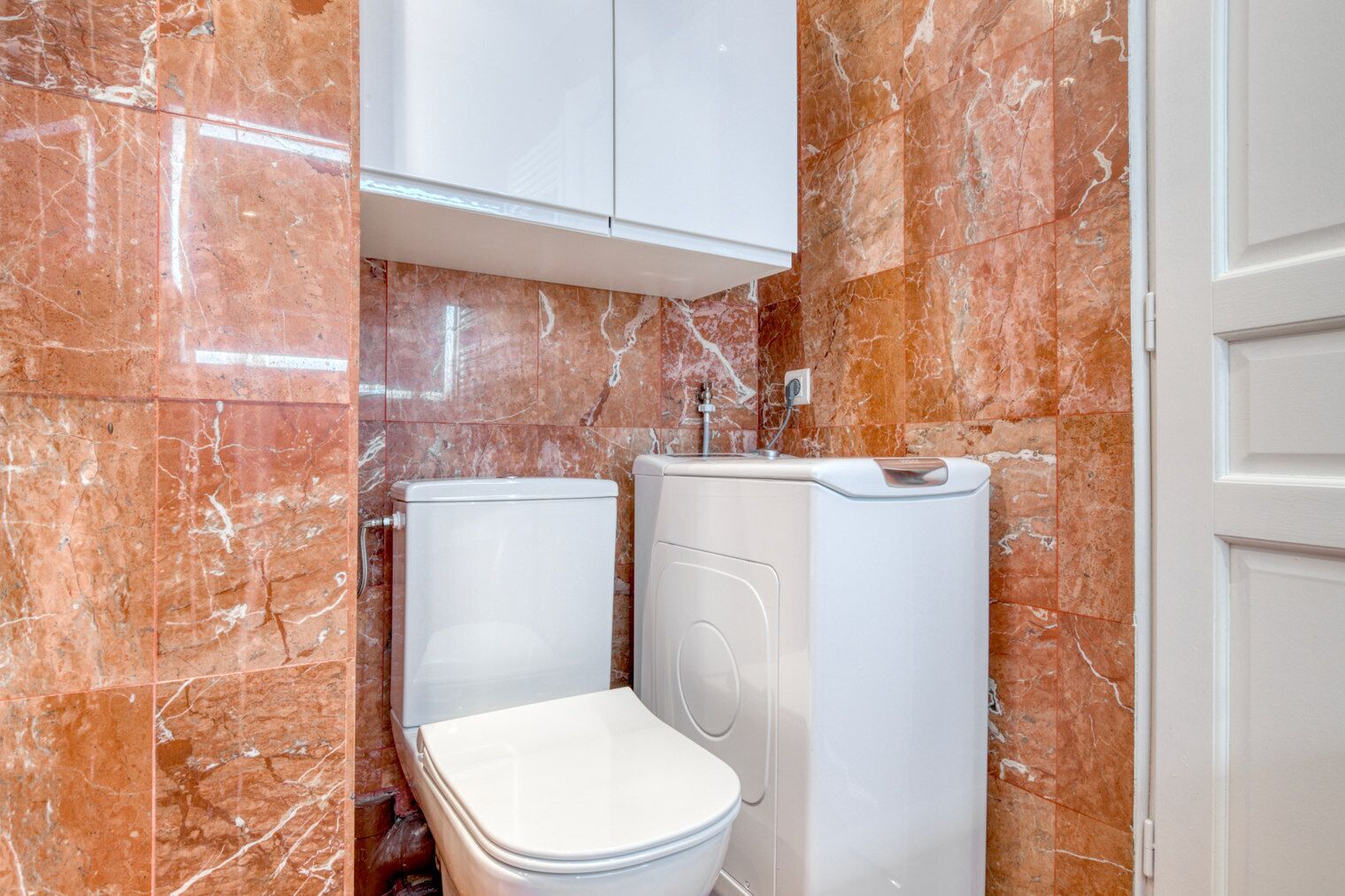 Un baño con inodoro, bidé y cabina de ducha frente a paredes de mármol.