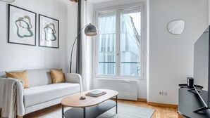 A modern living room with a sofa, coffee table, floor lamp, and a TV stand. - Blueground | Sèvres, near shopping (Paris)