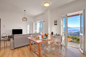 Un espace de vie moderne comprenant un coin repas, un canapé, un téléviseur et un balcon offrant une vue panoramique.