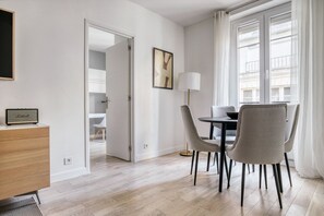 Enjoy meals and gatherings in this spacious room with a dining area, large window, and door leading to another room.